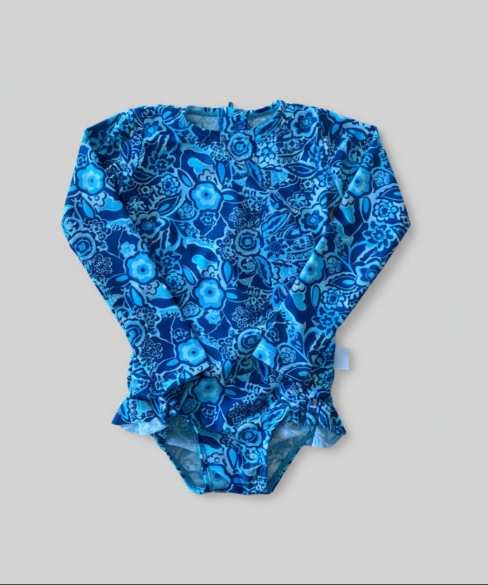 Blue floral-patterned baby romper on a wooden surface