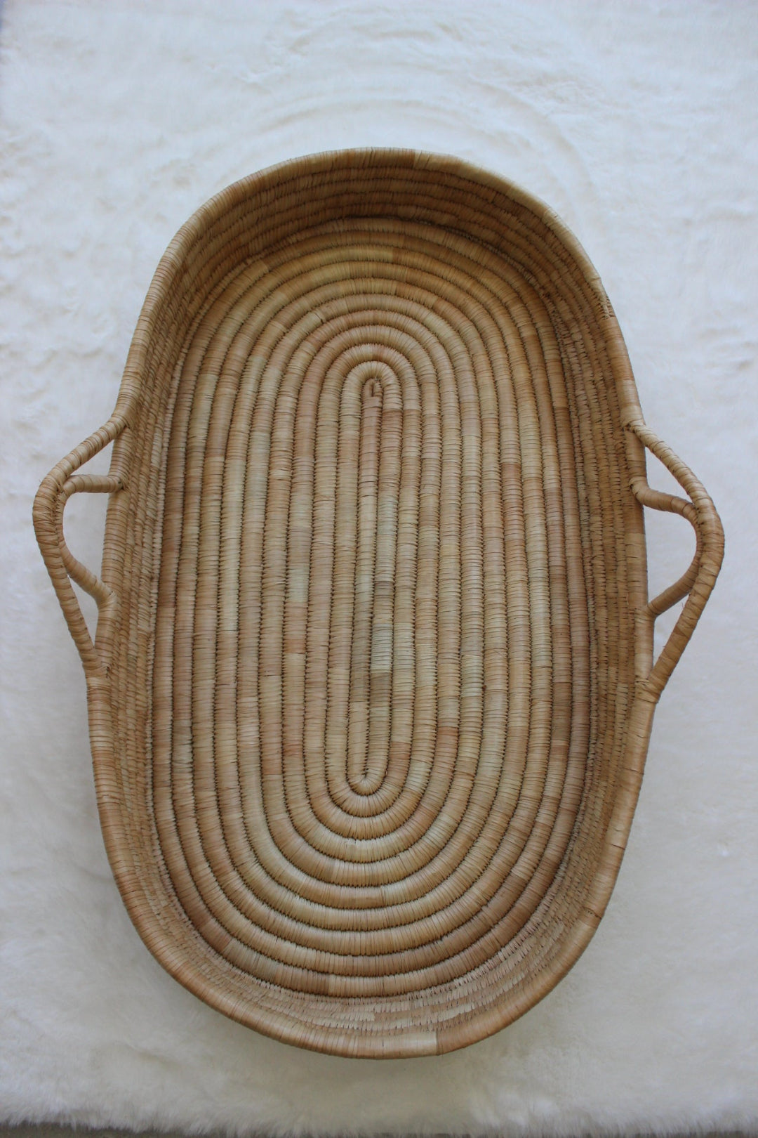 Woven moses basket with handles on a white background