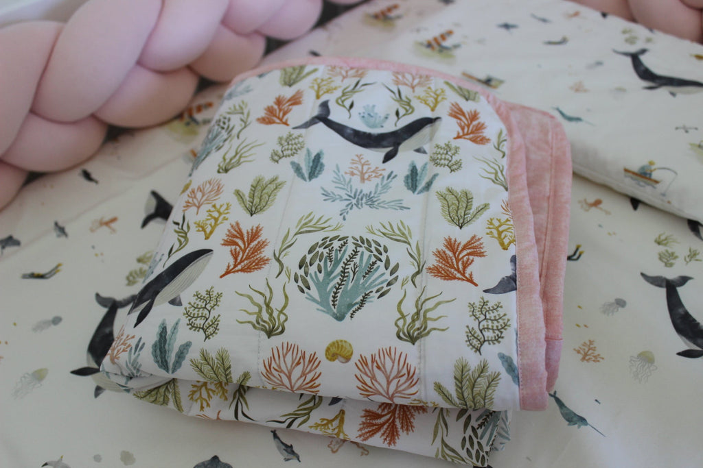 Folded fabric with animal and plant pattern held by a hand on a matching fabric background.