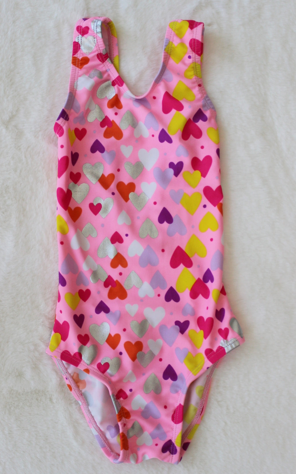 Pink swimsuit with colorful heart pattern on a light background