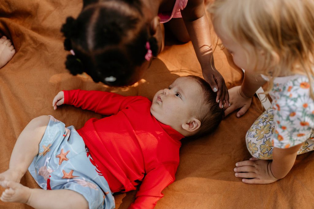 Children playing with a baby on a wooden floor