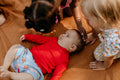 Children playing with a baby on a wooden floor