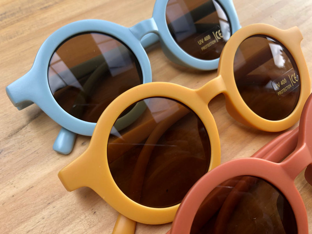Three pairs of colorful sunglasses on a wooden surface