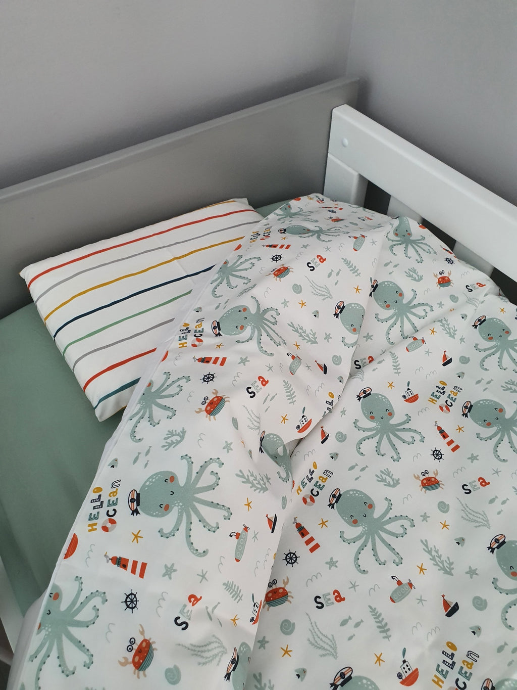 Children's bed with octopus-themed bedding and striped pillow