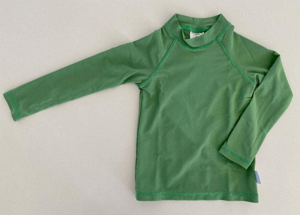A green long-sleeve rash vest laid flat on a light gray background, featuring matching green trim along the collar, sleeve cuffs, and hem.