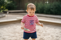 Red and white striped t-shirt with blue fish design playing in a sand pit