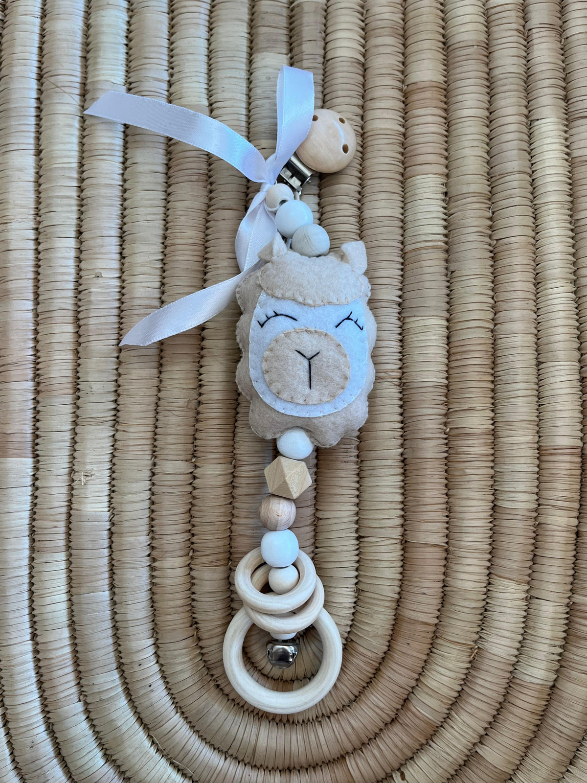 Baby llama pram dangle with soft toy on a woven surface