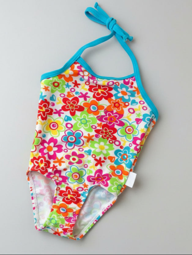 Colorful floral-patterned swimsuit with blue straps on a green grass background