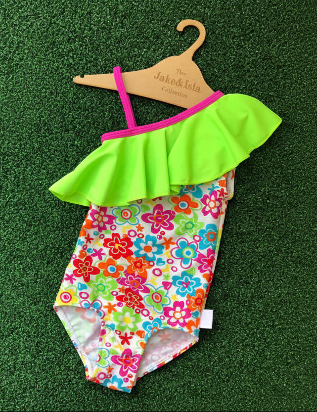 Colorful swimsuit with floral pattern and green ruffled top on a green background