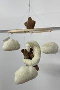 Baby mobile with teddy bears and clouds hanging from a rod against a white background