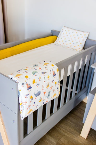 Children's crib with colorful bedding and yellow pillow