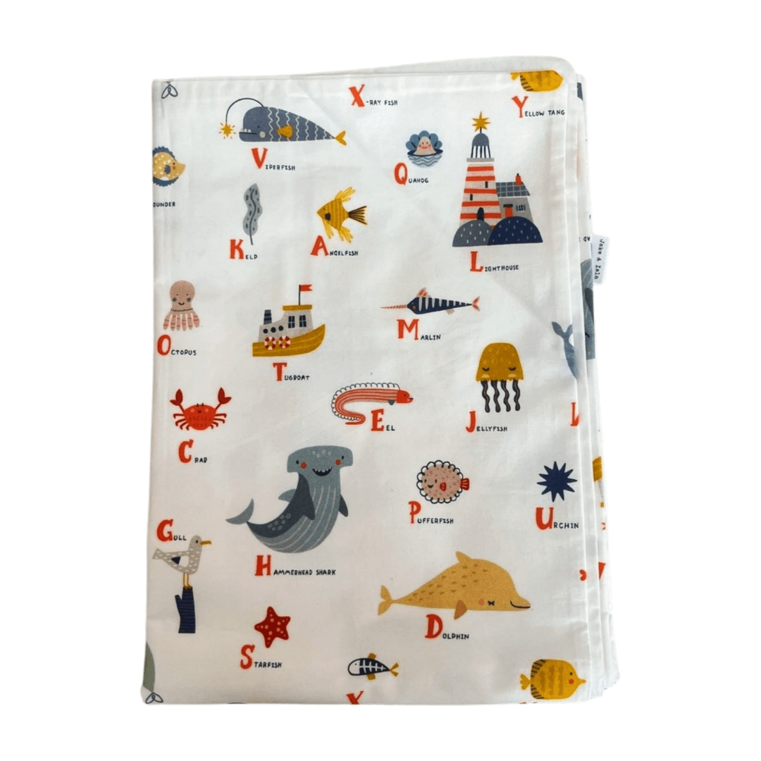 Children's blanket with alphabet and sea-themed illustrations on a white background