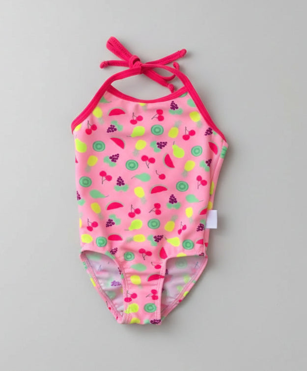 Pink children's swimsuit with colorful pattern on a green grass background
