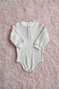 Textured baby onesie on a gray background
