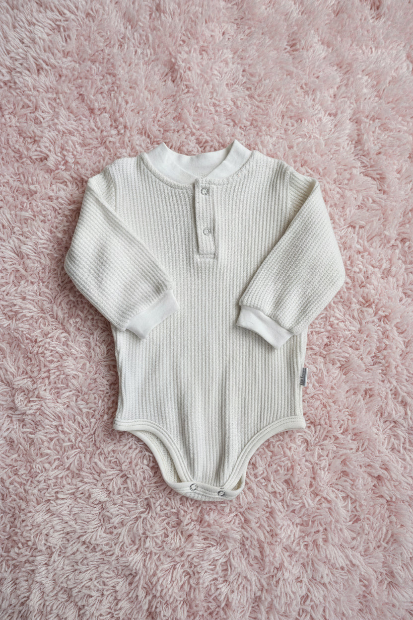Textured baby onesie on a gray background