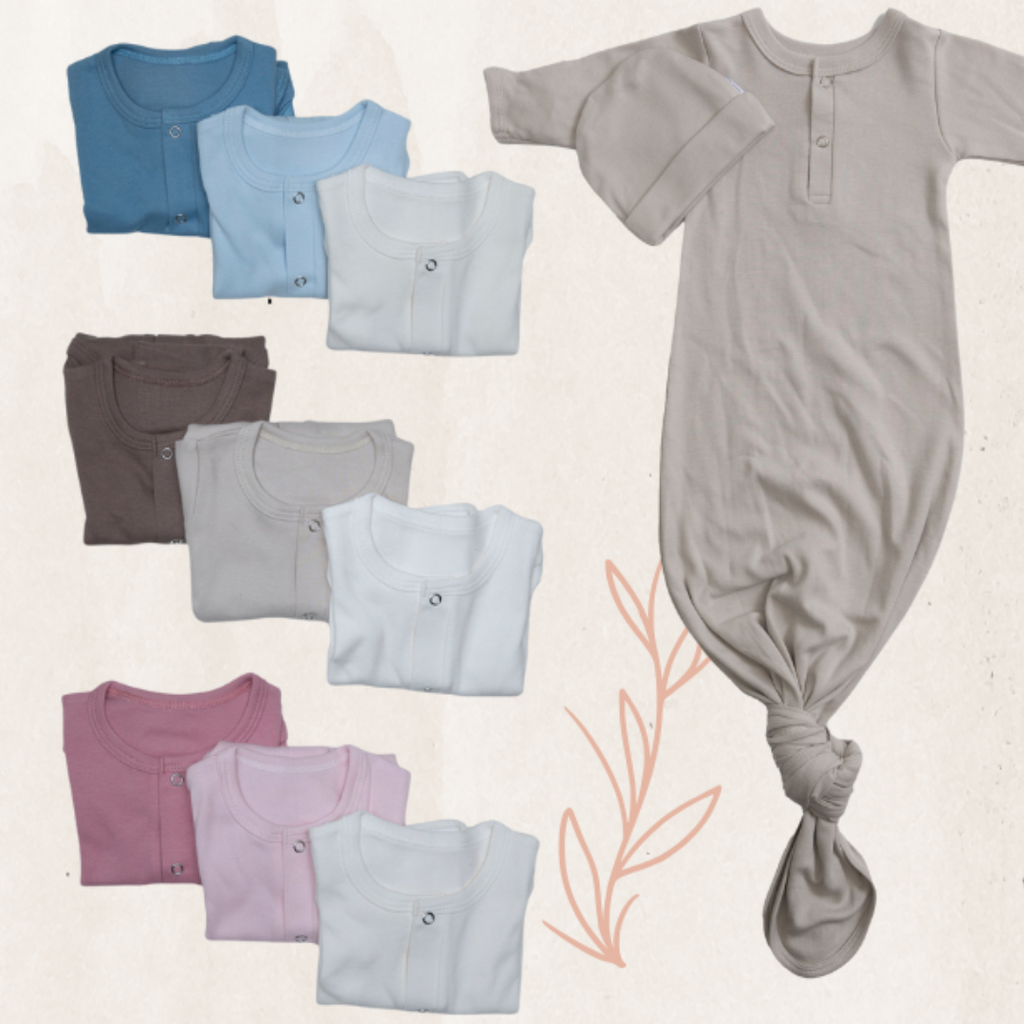 Collection of folded baby clothes including shirts and a onesie on a light background