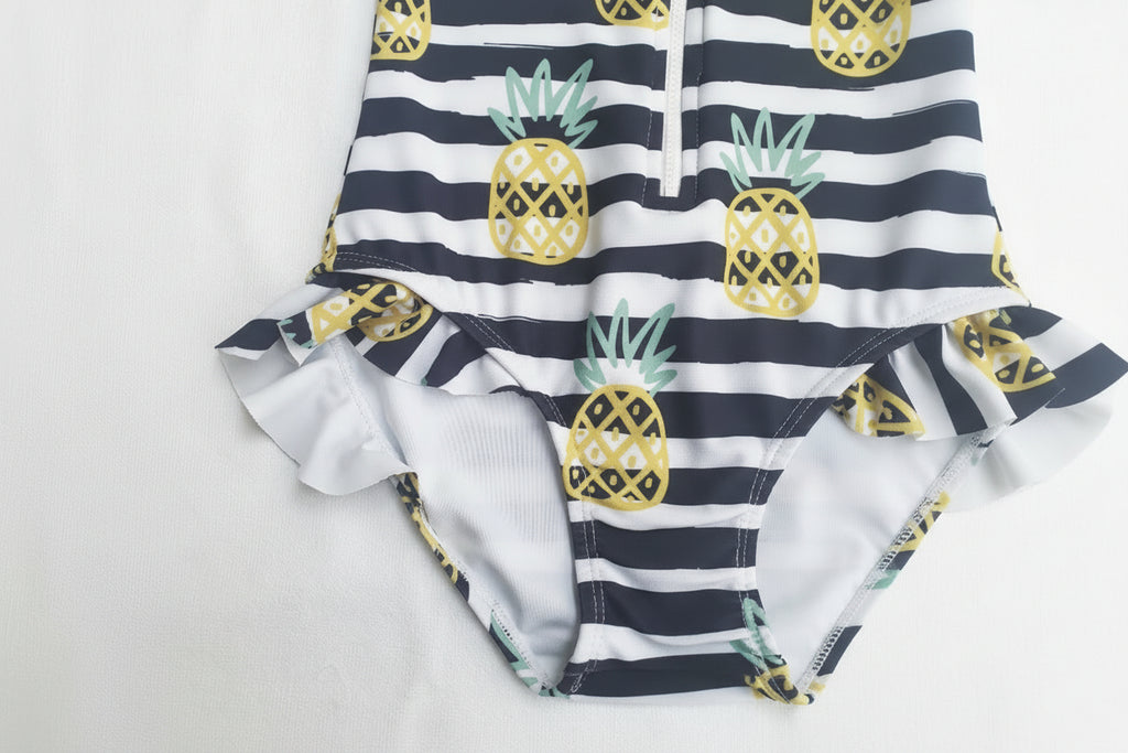 One-piece swimsuit with pineapple pattern and striped design on a light background