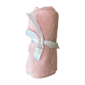 Pink knitted blanket with a white ribbon on a white background
