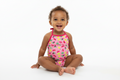 Pink children's swimsuit with fruit pattern on a white background