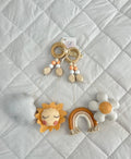 Baby mobile dangle with sun, rainbow, and cloud designs on a textured surface