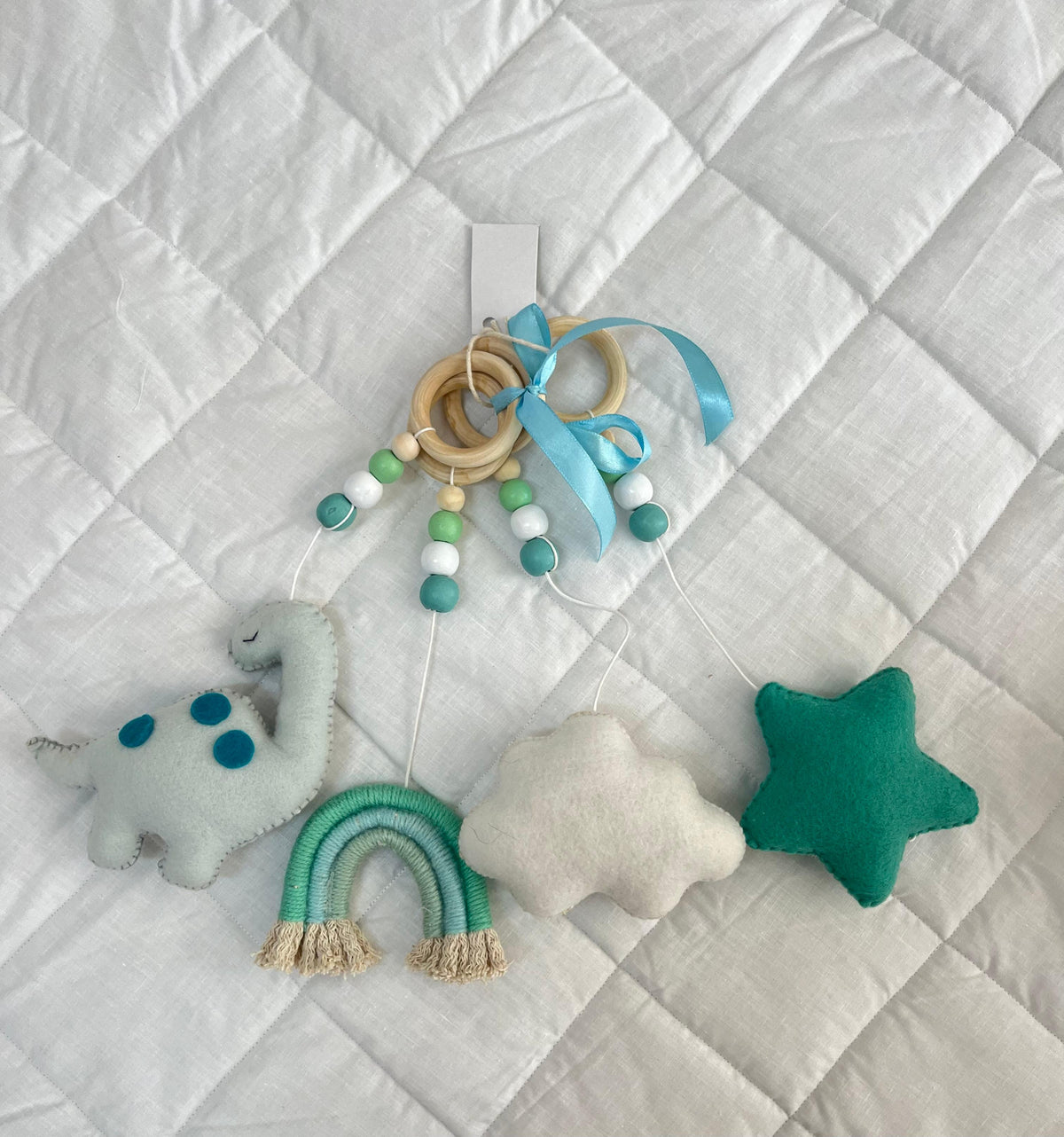 Baby mobile with dinosaur, cloud, and star toys on a textured white background