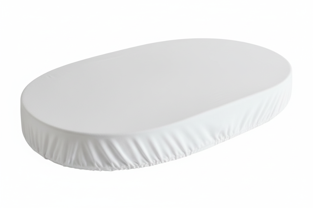 white fitted sheet on oval crib mattress on white background